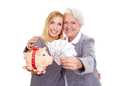 Young and old woman holding Euro money and a piggy bankの写真素材