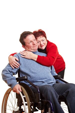 Elderly woman embracing her disabled man in wheelchairの写真素材