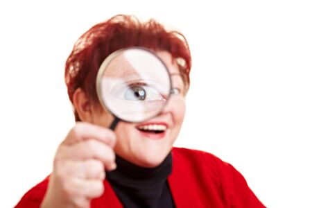Smiling elderly woman looking through magnifying glassの写真素材