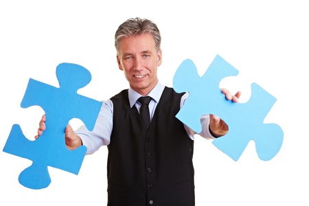 Senior manager holding two oversized blue jigsaw piecesの写真素材