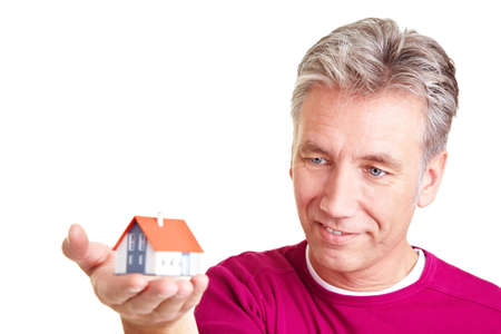 Senior man looking at a small miniature houseの写真素材