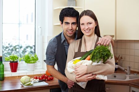 Happy couple with their groceries in the kitchenの写真素材