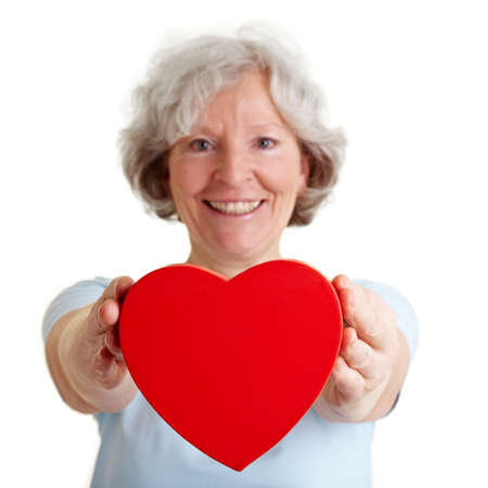 Smiling senior woman offering a red heartの写真素材