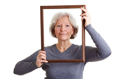 Smiling old woman looking through an empty frameの写真素材