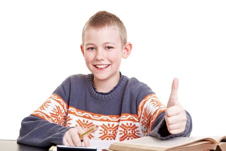 Happy boy on his desk with homework holding his thumb up