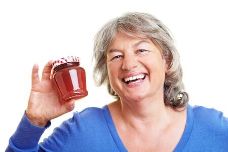Elderly woman holding a glass of homemade jamの写真素材