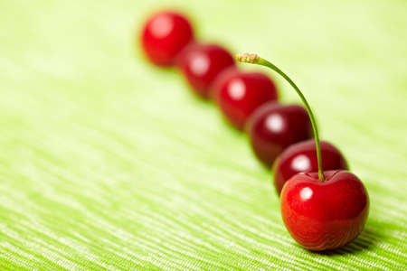 Red sweet cherries behind on a green tableclothの写真素材