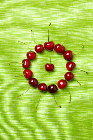 Many red cherries in a circle on green backgroundの写真素材