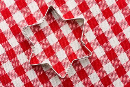 Star shaped cookie cutter on a red-white striped tableclothの写真素材