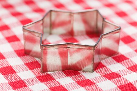 Star shaped christmas cookie cutter on striped tablecloth