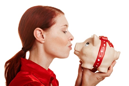 Redhaired woman kissing a big piggy bankの写真素材