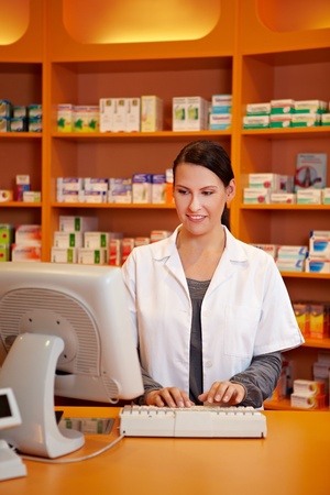 Pharmacist ordering medicine with computer in a drugstoreの写真素材