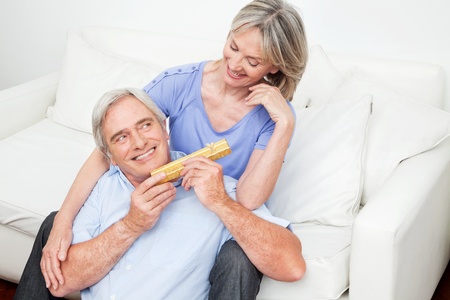 Senior giving his smiling woman a valentines day giftの写真素材