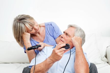 Married senior couple competing at video game with controllersの写真素材