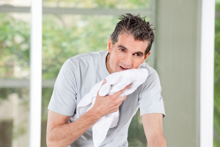 Sweating man using a towel in fitness centerの写真素材