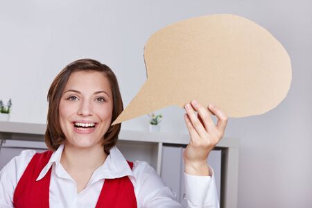 Happy business woman in offce holding empty cardboard speech balloon