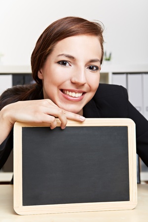 Happy business woman showing empty black chalkboardの写真素材