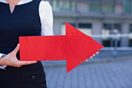 Business woman holding red arrow pointing to the rightの写真素材