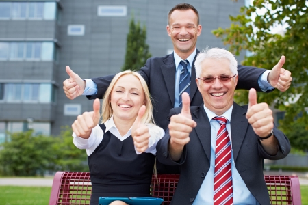 Happy business people holding their thumbs up outsideの写真素材