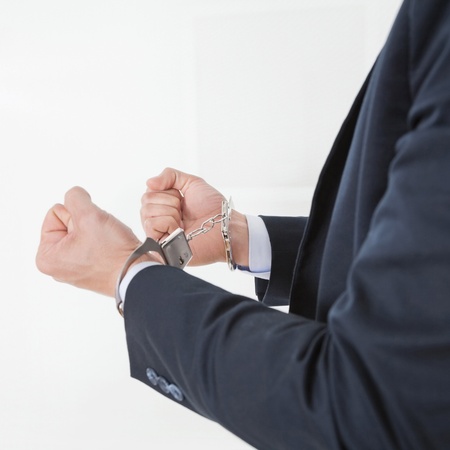 Businessman in handcuffs getting arrested for white collar crimesの写真素材