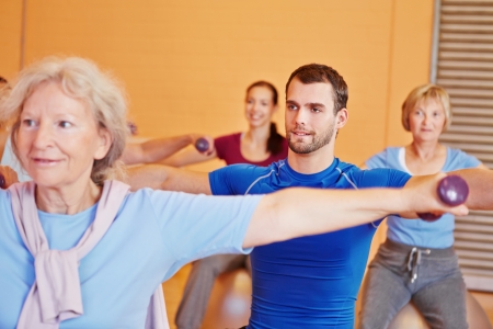 Young man lifting dumbbells in back training class in gym