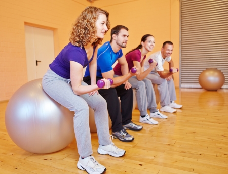 Young people in back training class in a fitnesscenter with dumbbellsの写真素材