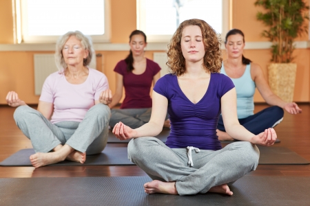 Group of women doing relaxing yoga exercises in gymの写真素材