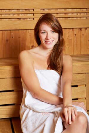 Brunette woman sitting smiling in a saunaの写真素材