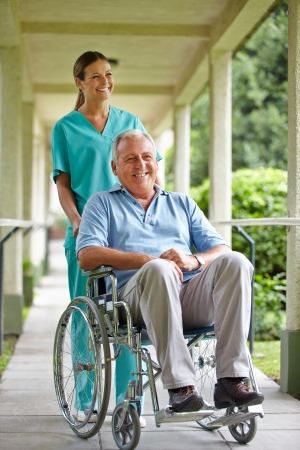 Senior man in wheelchair with nurse in the park of a hospitalの写真素材