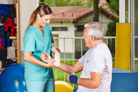 Nurse changing bandage on wrist of senior man at physiotherapyの写真素材