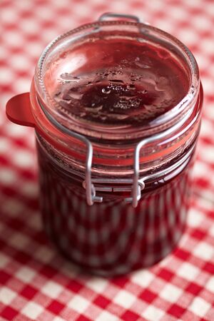 Preserving jar with homemade amarena cherries on tablecloth