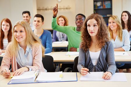 African student lifting hand in classroom of university seminarの写真素材