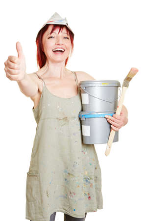 Happy painter with brush and paint buckets holding thumbs upの写真素材