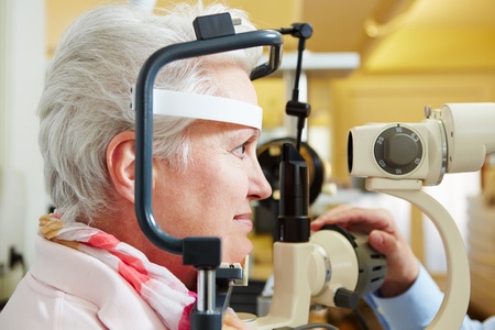 Senior woman getting her cornea checked with slit lamp at optician
