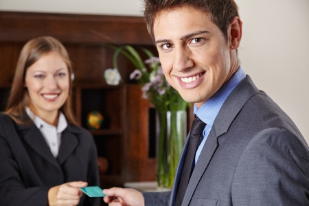 Smiling businessman in hotel getting his key card at the receptionの写真素材