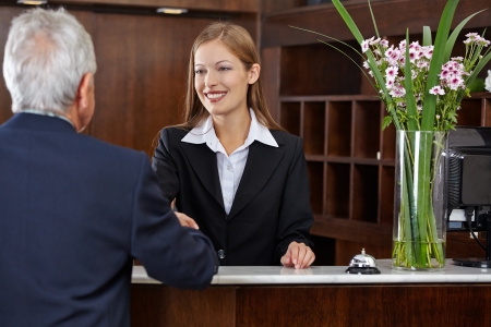 Smiling female receptionist greeting a senior guest with handshakeの写真素材