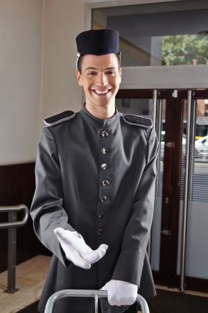 Happy concierge in uniform standing in a hotel lobbyの写真素材