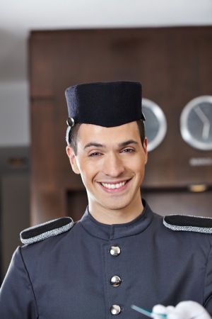 Happy hotel concierge smiling with key card in his handの写真素材