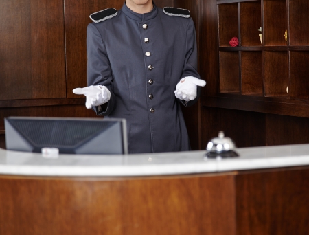 Concierge with empty white gloves behind hotel reception counterの写真素材