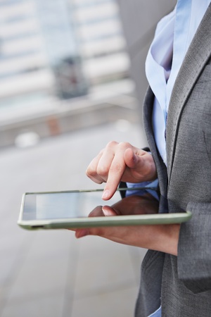 Woman typing with finger on her tablet computer outdoorsの写真素材
