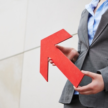 Red arrow pointing up and is held by womanの写真素材