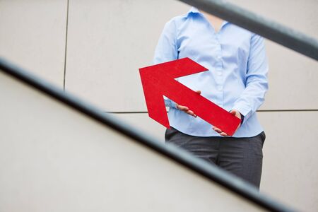 Woman holding red big arrow pointing upwards