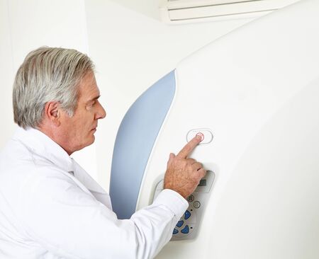 Elderly radiologist pressing button at MRI in hospital