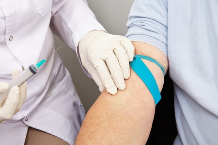 Doctor with syringe at blood withdrawal looking for a blood vessel