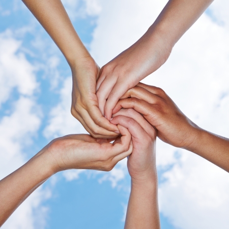 Many hands connecting for help in a spiral under a skyの写真素材