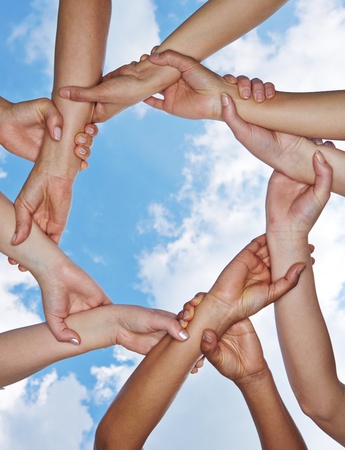 Group of many hands forming a chain under a skyの写真素材