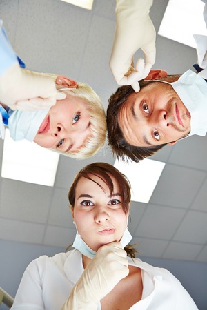 Dentist and dental assistants looking pensive at patient POVの写真素材