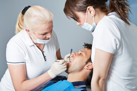 Dental assistant watching dentist at work with a patientの写真素材