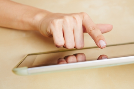 Hand of a woman typing on a tablet computer with the index fingerの写真素材