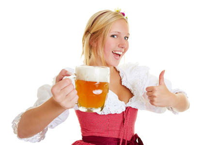 Happy woman in a dirndl with a mug of beer holding her thumbs upの写真素材